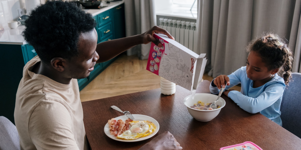 A parent and child sharing a morning meal at home, illustrating the everyday routines made possible by stable housing.