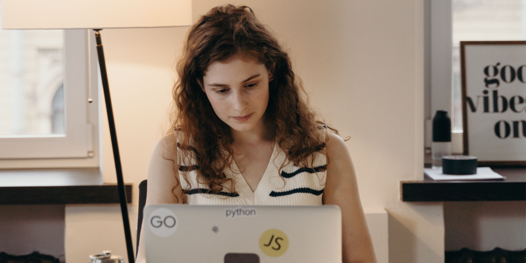 A woman concentrates on work at a laptop in an office.