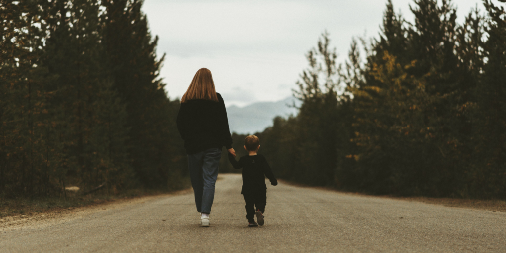 A parent and child holding hands while walking together.